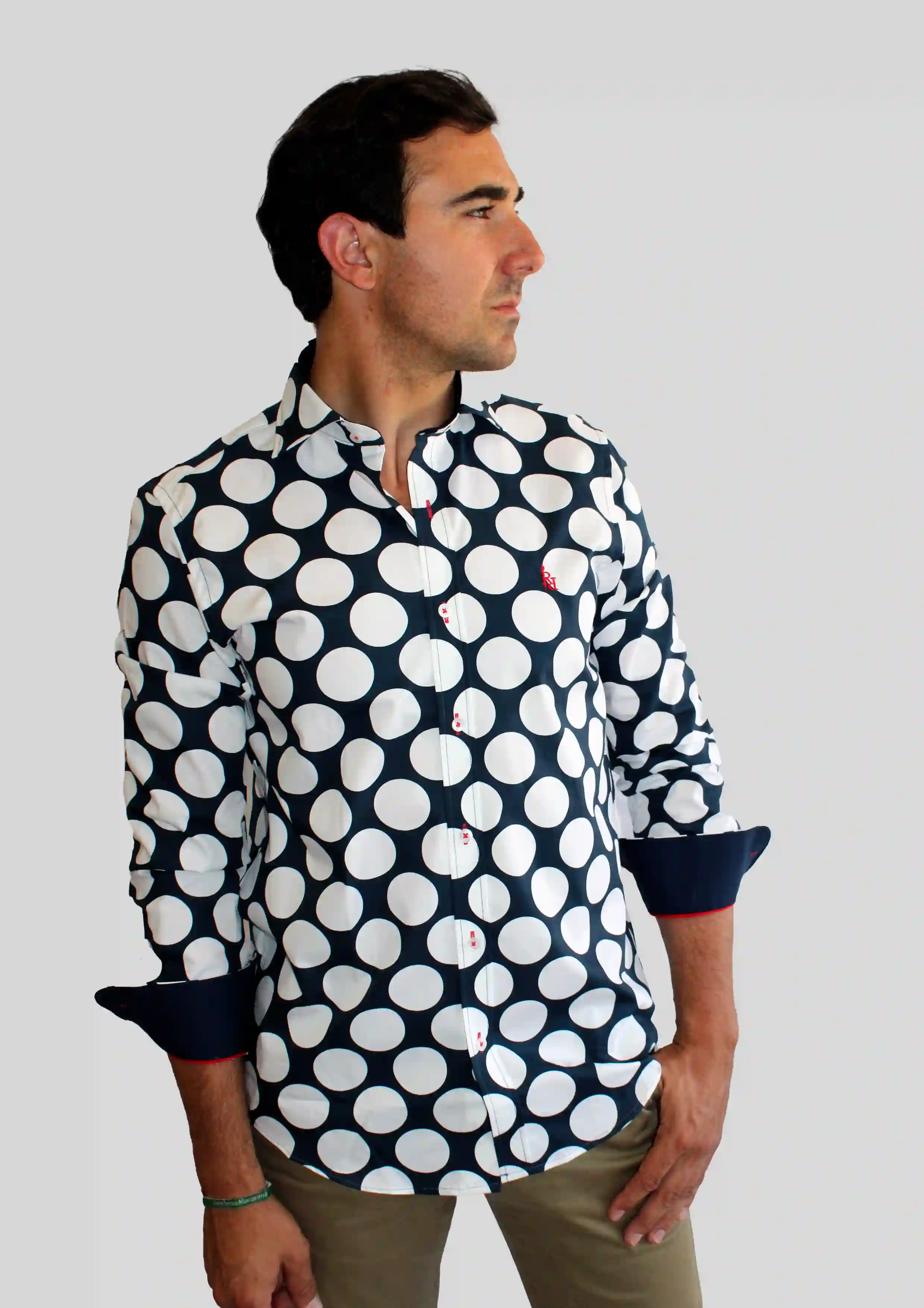 Camisa de lunares azul marino con logo bordado rojo.