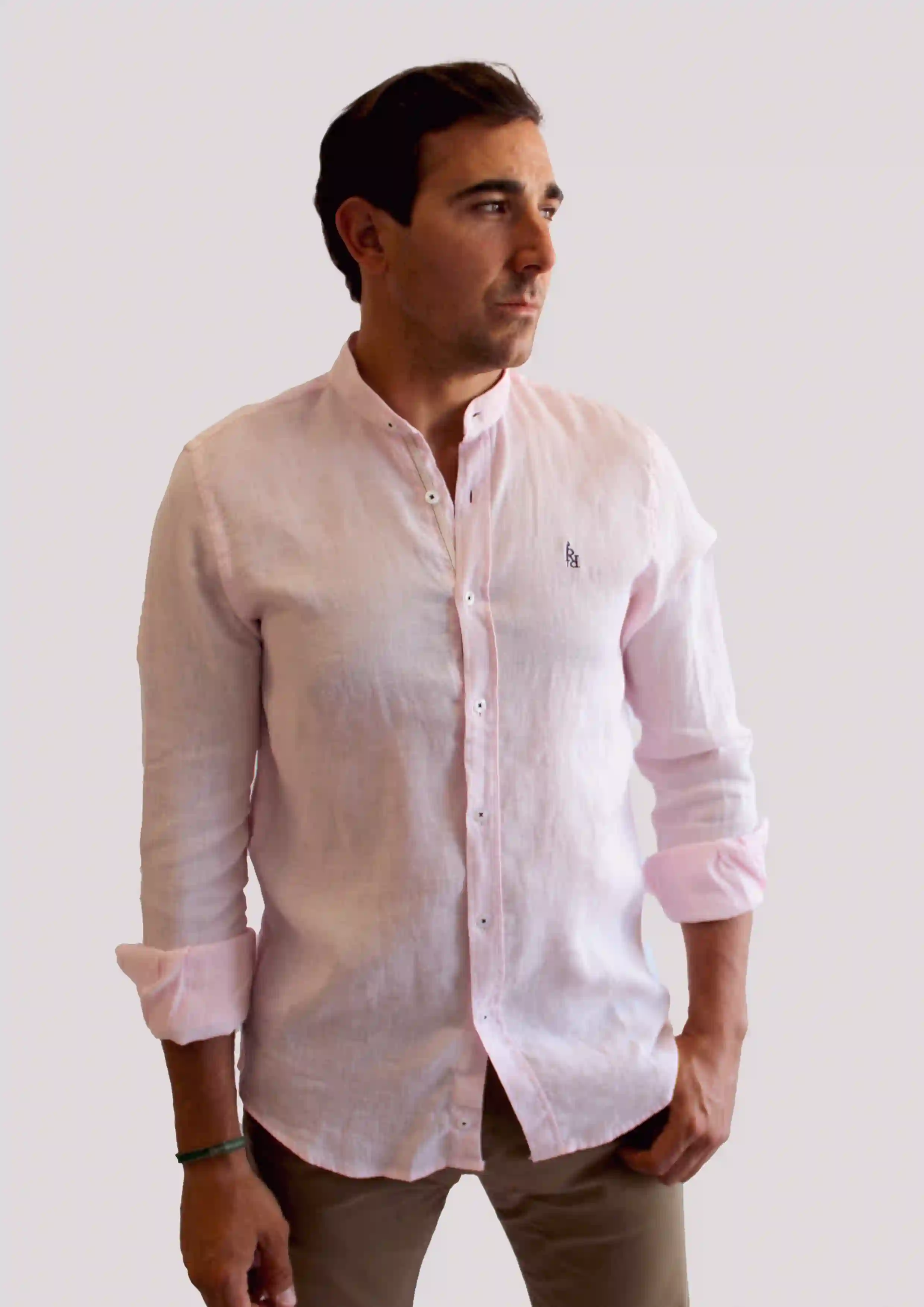 Camisa de lino en rosa claro con logo bordado en azul oscuro.