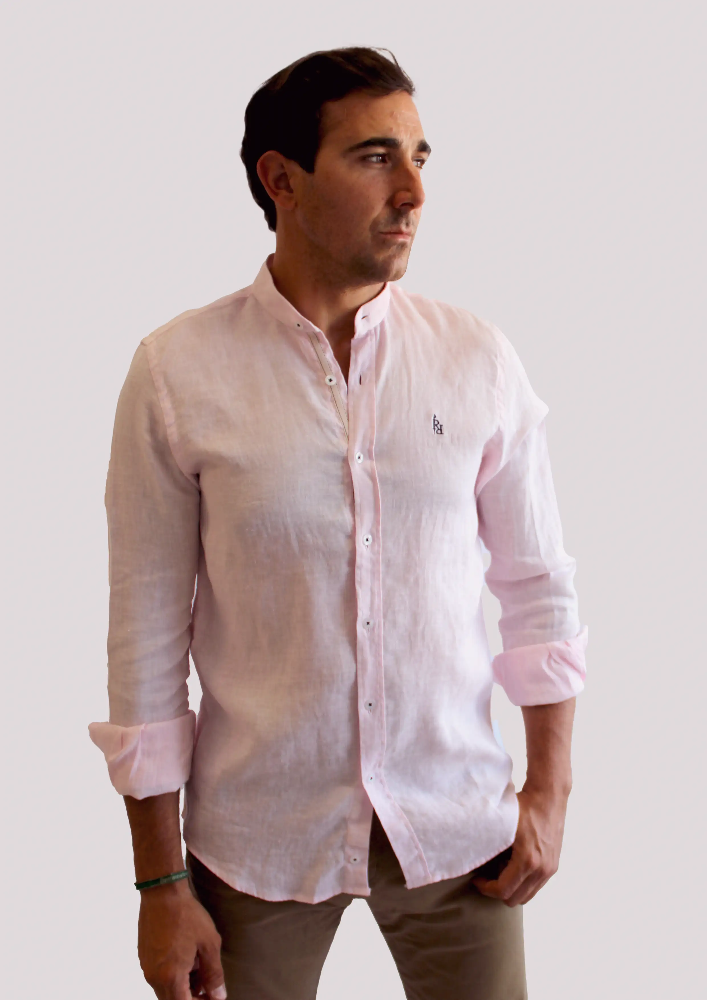 Camisa de lino en rosa claro con logo bordado en azul oscuro.
